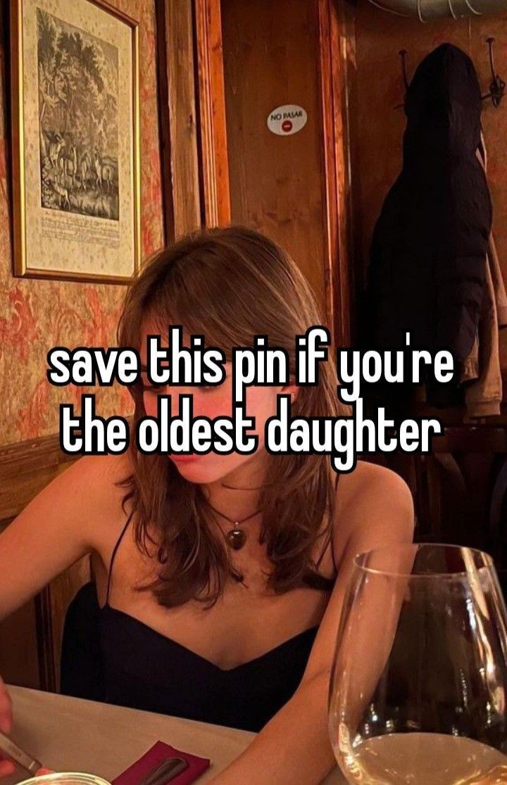 a woman sitting at a table in front of a wine glass with the words save this pin if you're the oldest daughter