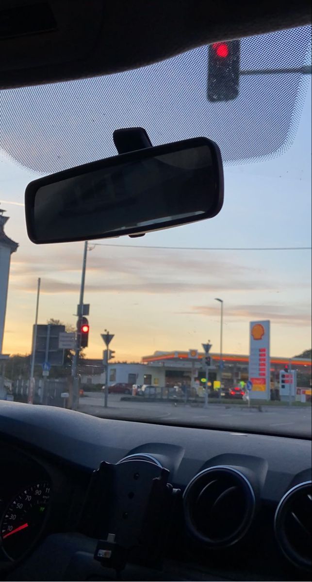 the view from inside a car looking at a gas station and traffic lights in the distance