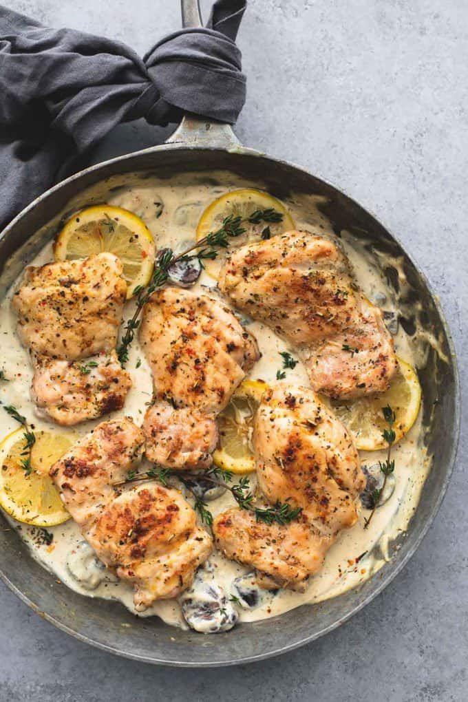 a pan filled with chicken and lemons covered in white sauce on top of a table