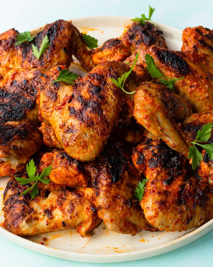 a white plate topped with chicken wings and garnished with parsley