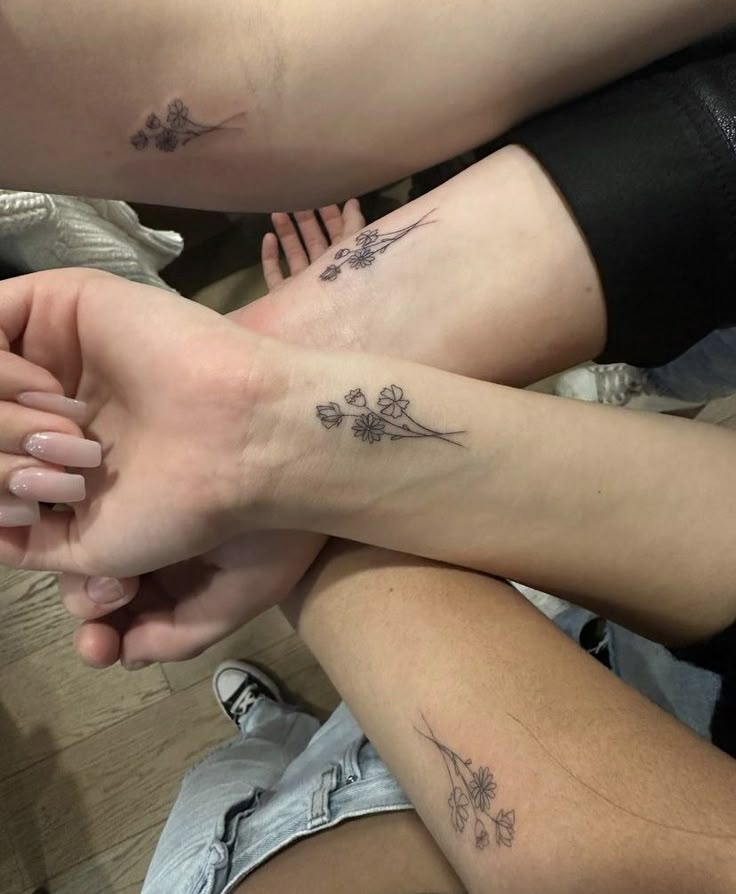 two people holding hands with tattoos on them