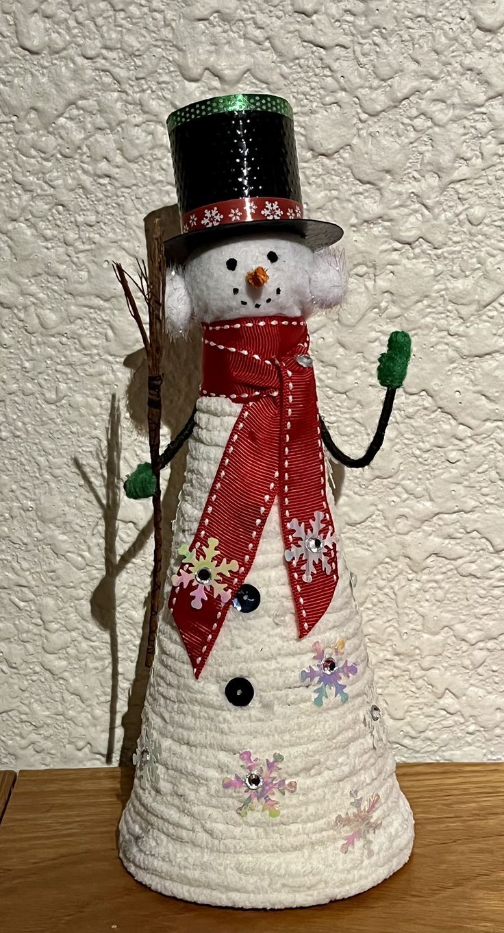 a snowman with a top hat and red scarf is standing on a wooden table