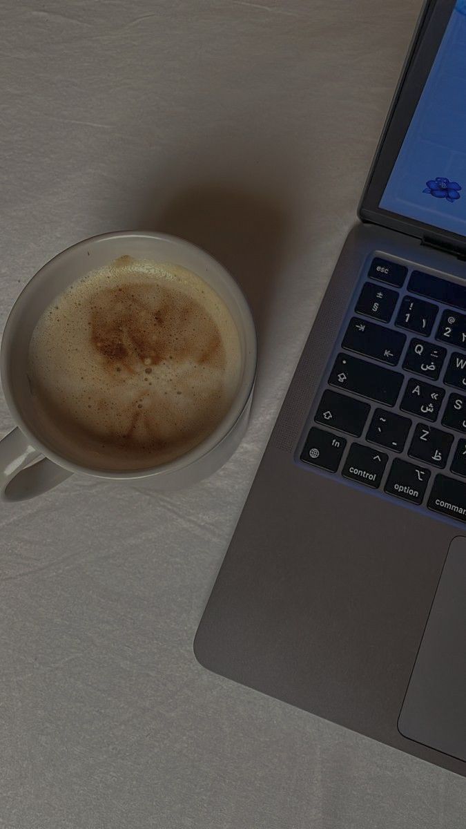 an open laptop computer sitting next to a cup of coffee