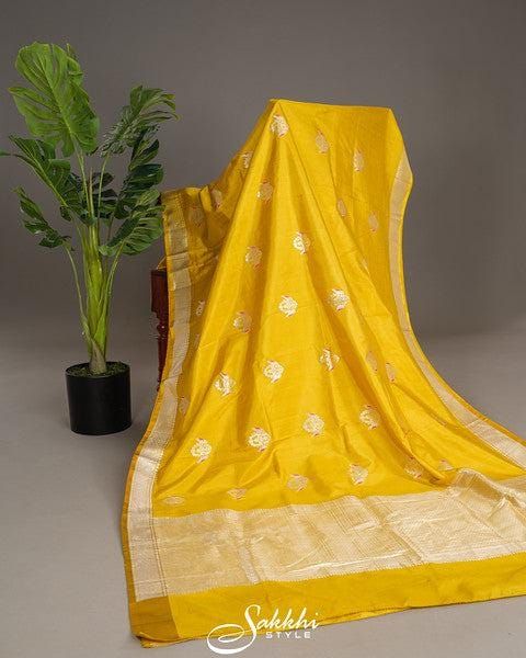 Sunshine yellow radiates warmth in the Banarasi silk saree, its silver zari birds taking flight amidst hints of pink Resham's gentle blush. The tonal blouse's soft harmony complements the saree's vibrant drape, as elbow sleeves frame the beauty within. This bright ensemble is a symphony of joy, weaving happiness and warmth into every thread, draping the wearer in a ray of sunshine elegance. * Banarasi katan silk saree for special occasions. * Crafted from the premium quality fabric. * Supplied with a readymade blouse. * The blouse comes with an added allowance, and it can be altered to a standard size of 34"-42" on request. * Dry clean only to maintain colour and quality. Note: Colors may slightly vary due to photographic lighting. We provide same day shipping for orders placed before 3pm Transitional Yellow Art Silk Kurta, Transitional Season Yellow Art Silk Kurta, Yellow Slub Silk Kurta With Pallu, Yellow Slub Silk Kurta With Pallu Detail, Elegant Yellow Saree With Gota Work, Yellow Handloom Kurta For Festivals, Yellow Silk Traditional Wear For Transitional Season, Transitional Yellow Silk Traditional Wear, Yellow Slub Silk Dupatta With Gota Work