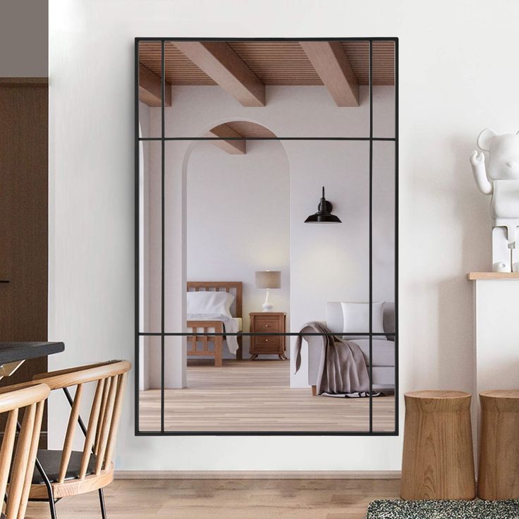 a large mirror in the middle of a room next to a wooden table and chair