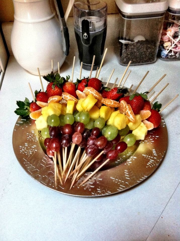 a platter filled with fruit and skewers on top of a kitchen counter