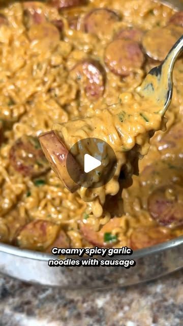 a spoon full of food is being held up by someone's hand with the word creamy spicy garlic noodles on it