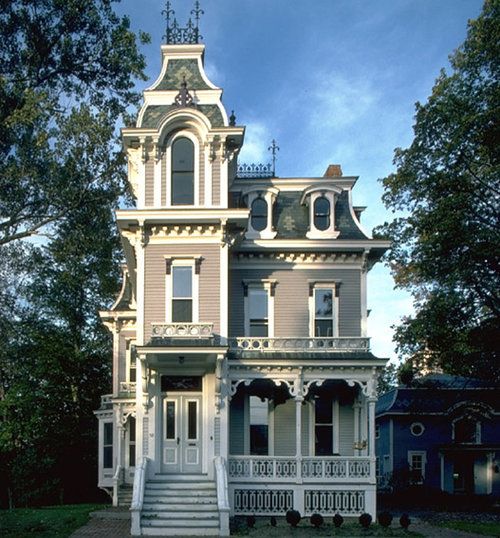 an old victorian style house with white trim on the front porch and stairs leading up to the second floor