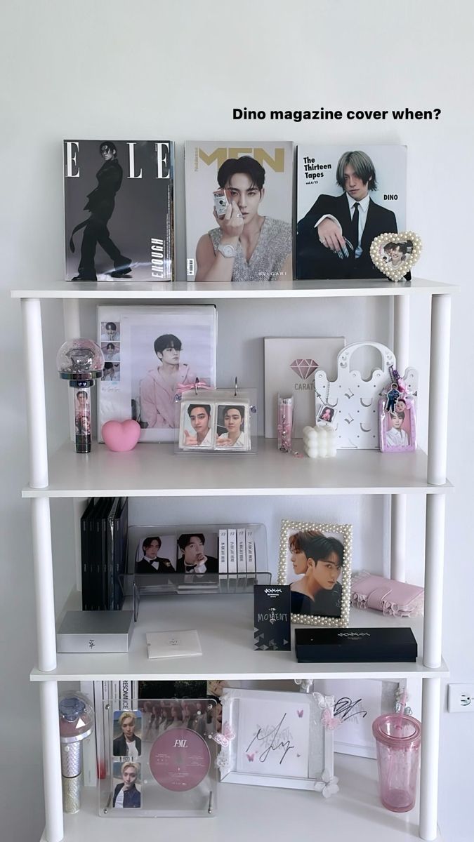 a white book shelf filled with books and pictures next to a pink vase on top of it