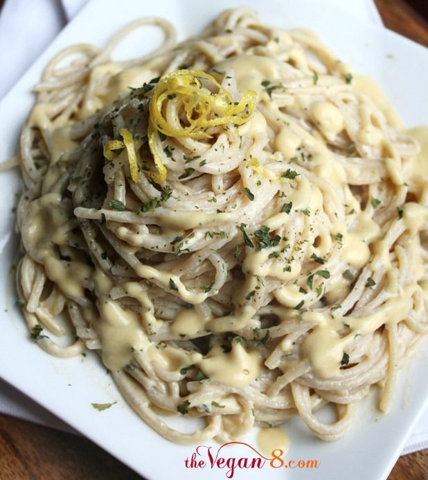 a white plate topped with pasta covered in gravy and lemon zest sauce