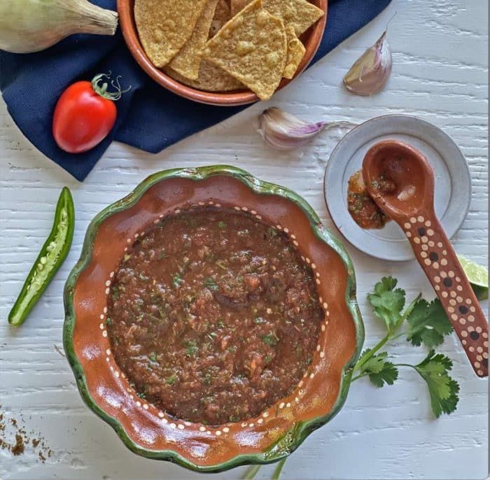 a bowl of chili and tortilla chips on a table with other food items