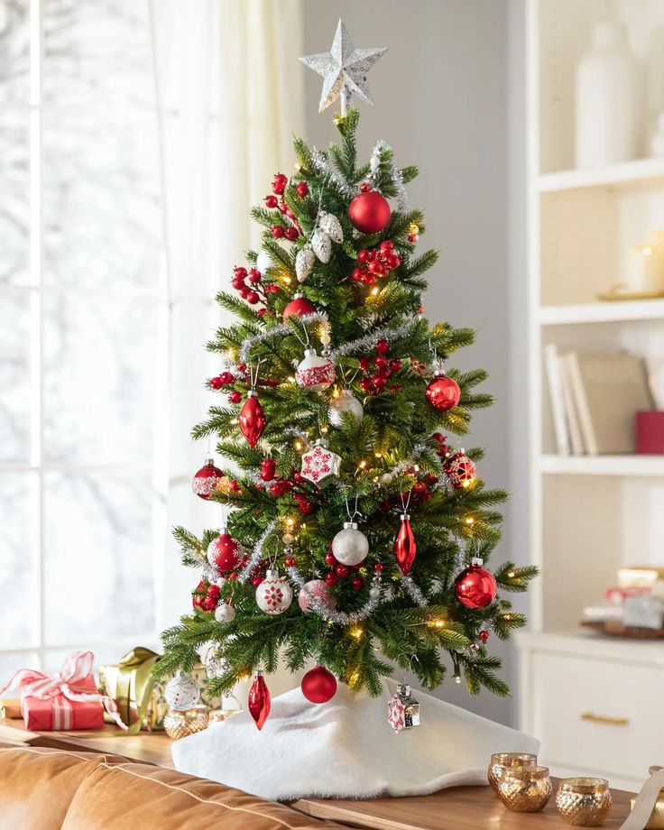 a small christmas tree with red and silver ornaments