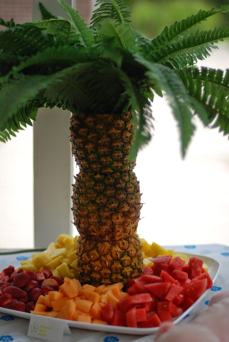 a pineapple and other fruits are arranged in the shape of a palm tree on a table