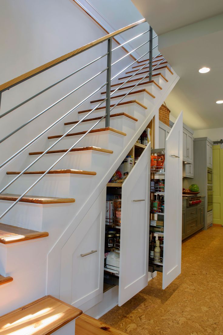 a kitchen under the stairs with storage underneath