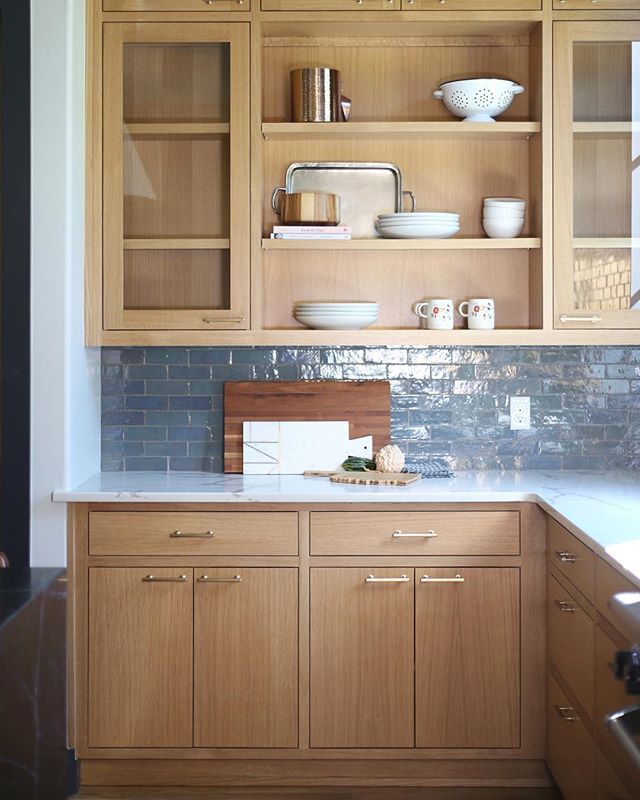 a kitchen with wooden cabinets and white counter tops in front of a blue tile backsplash