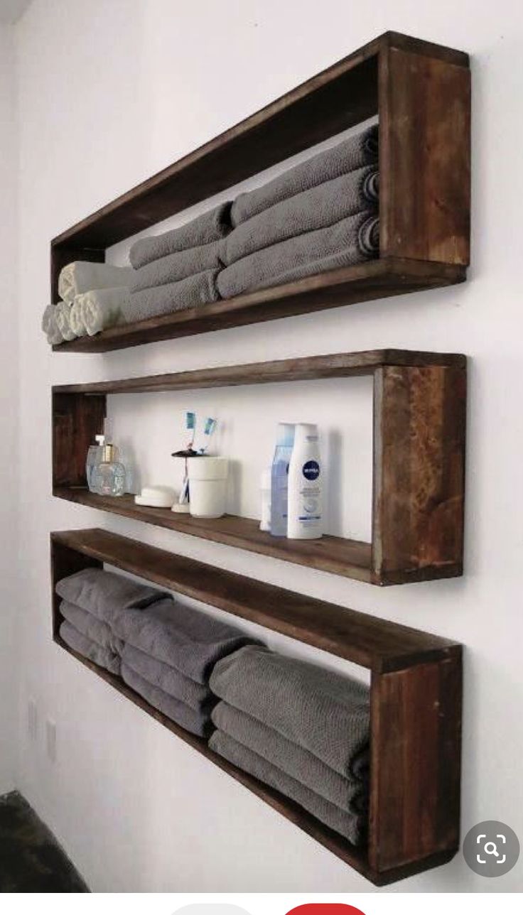 two wooden shelves holding towels and other bathroom items