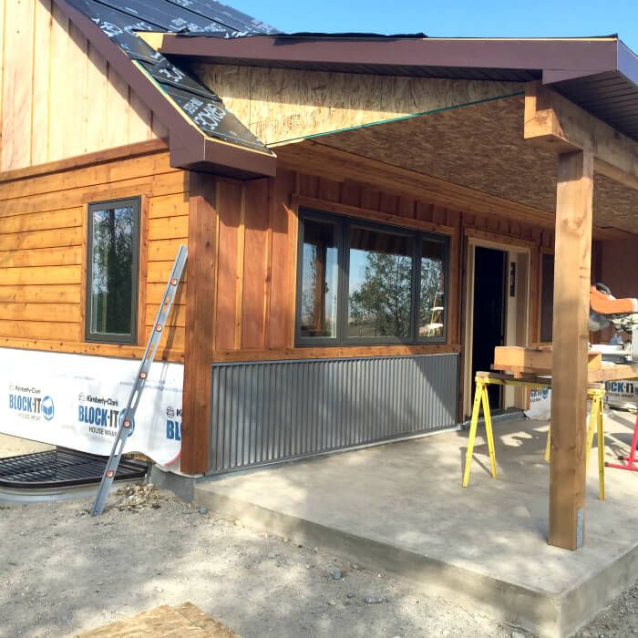 a house being built with wood siding and metal roofing on the front porch area