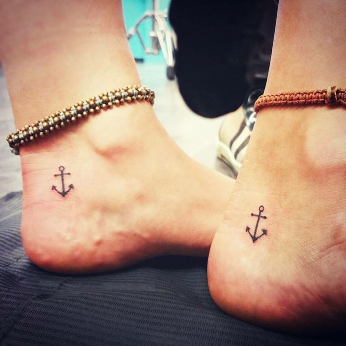 two people with matching tattoos on their feet, one has an anchor and the other has a cross