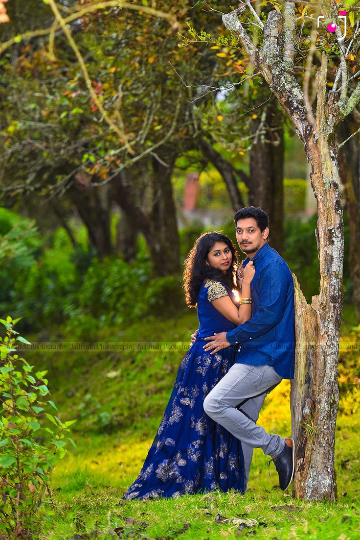 a man and woman standing next to each other near a tree