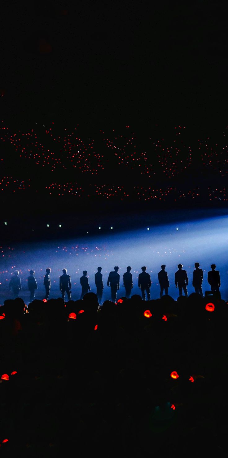 a group of people standing in the dark with pumpkins lit up at night time