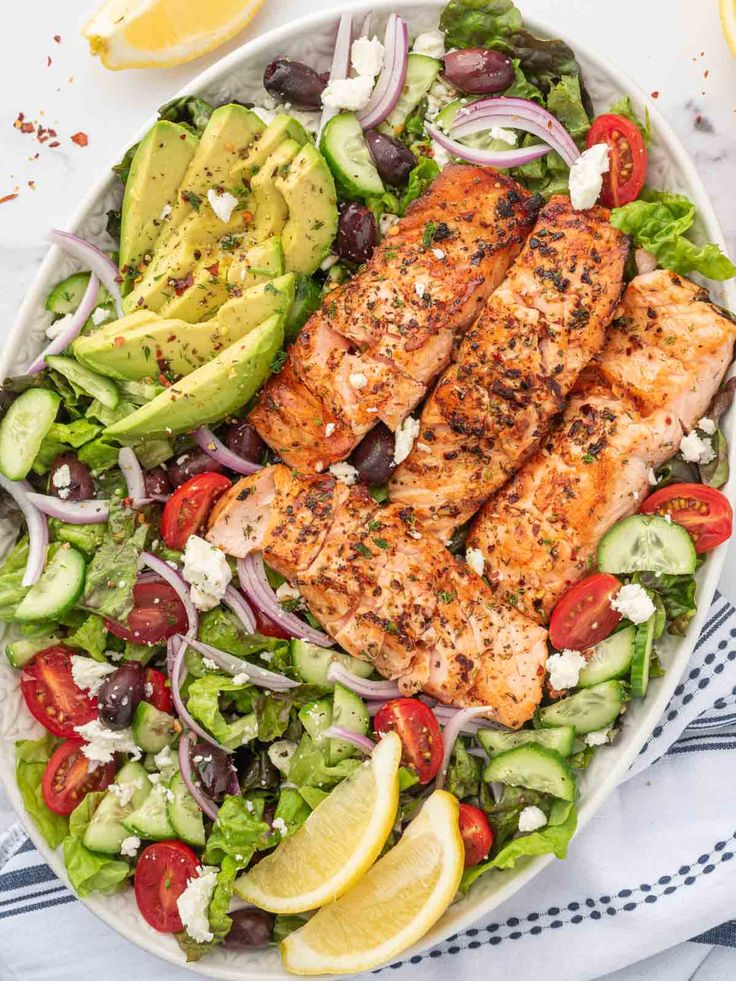 salmon and cucumber salad in a bowl with lemon wedges on the side