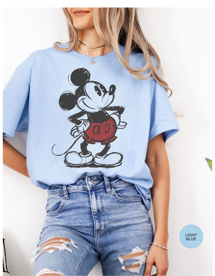 a woman wearing a blue mickey mouse t - shirt with the word disney on it