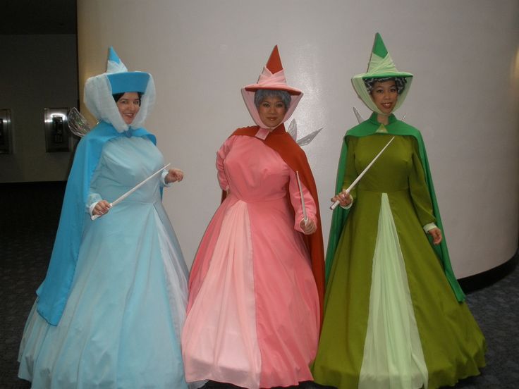 three women dressed in costume standing next to each other with hats and wands on their heads