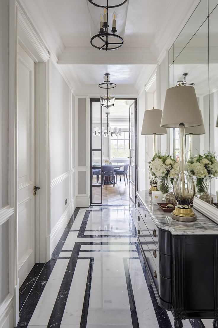 a long hallway with black and white striped flooring next to a dining room table