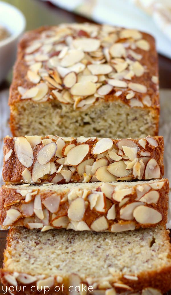 three slices of banana bread with almonds on top and one slice cut from the loaf