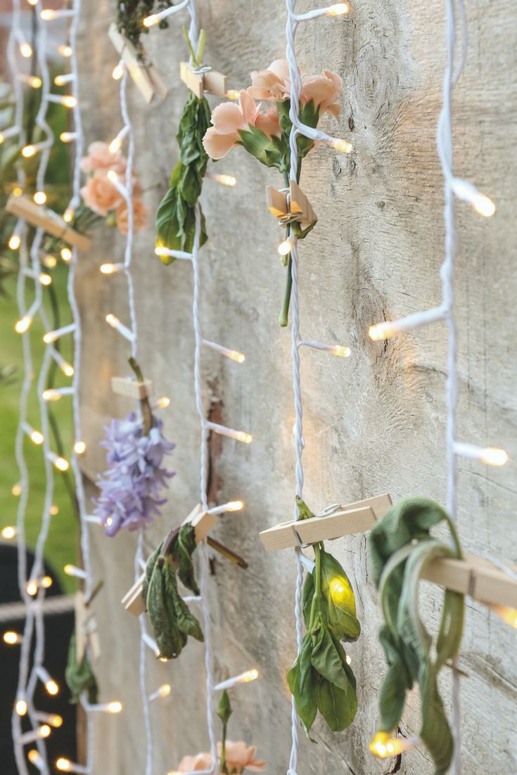 some flowers are hanging on the side of a building with lights strung from it's sides