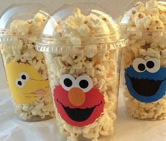 three plastic cups filled with popcorn topped with sesame the cookie monster and elm street characters