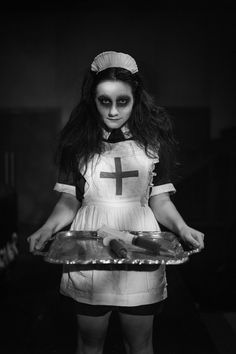 black and white photograph of a woman dressed as a nurse holding a tray with cookies on it