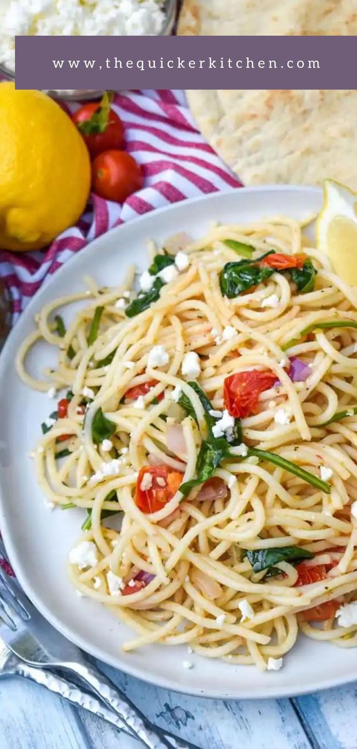 a plate of pasta with spinach, tomatoes and fettuccine on it