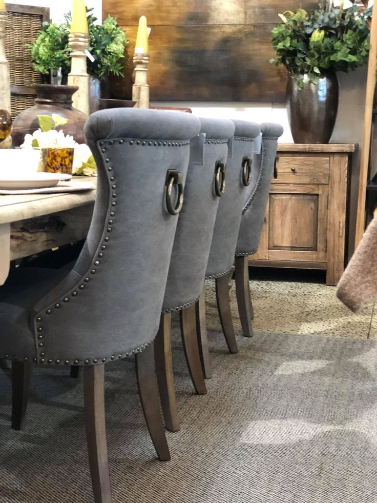 a set of four grey chairs sitting on top of a carpeted floor next to a table