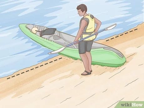 a man standing on the beach with his kayak