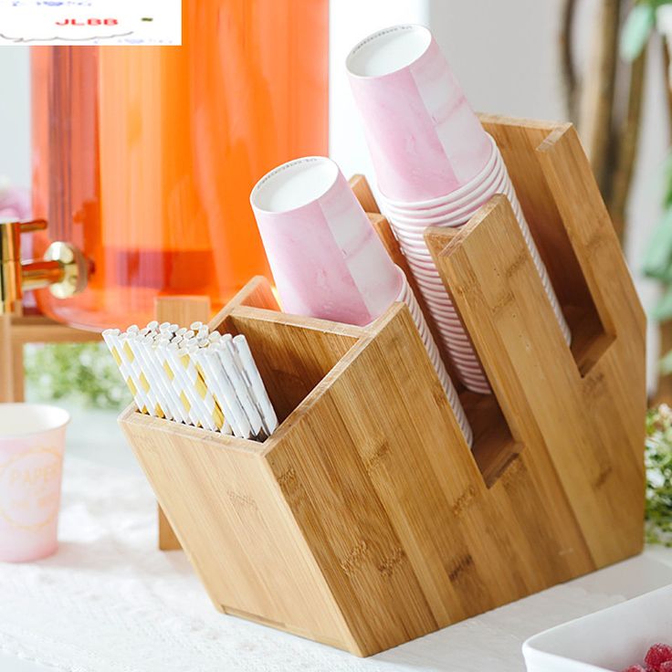 two bamboo containers with cups in them on a table