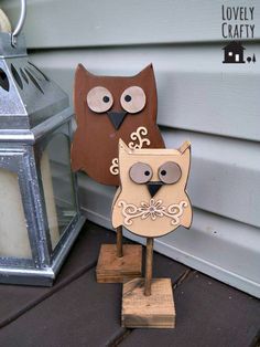 two wooden owls sitting on top of each other next to a light pole and lantern