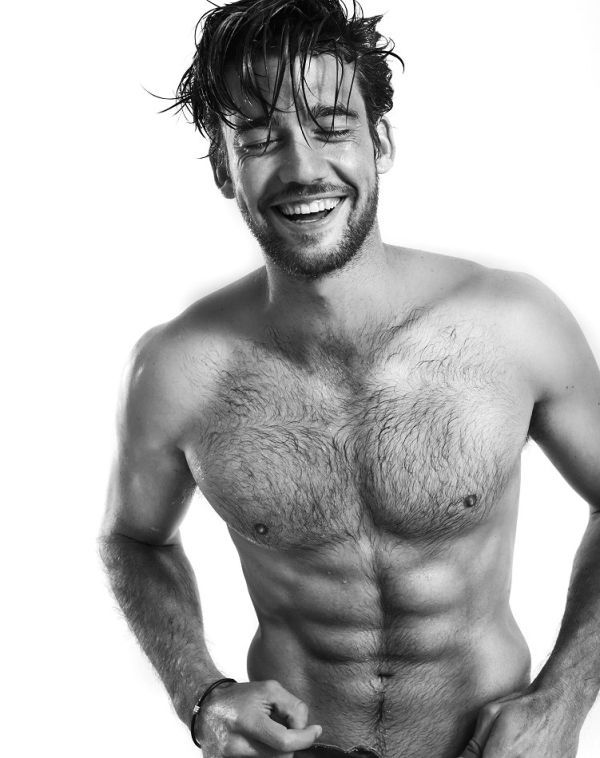 a shirtless man with his hands on his hips smiling at the camera while standing in front of a white background