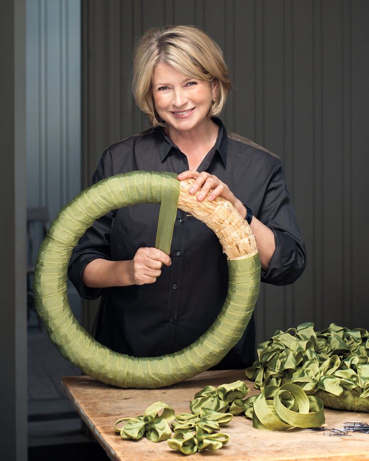 a woman holding a large green object in front of a table with other items on it