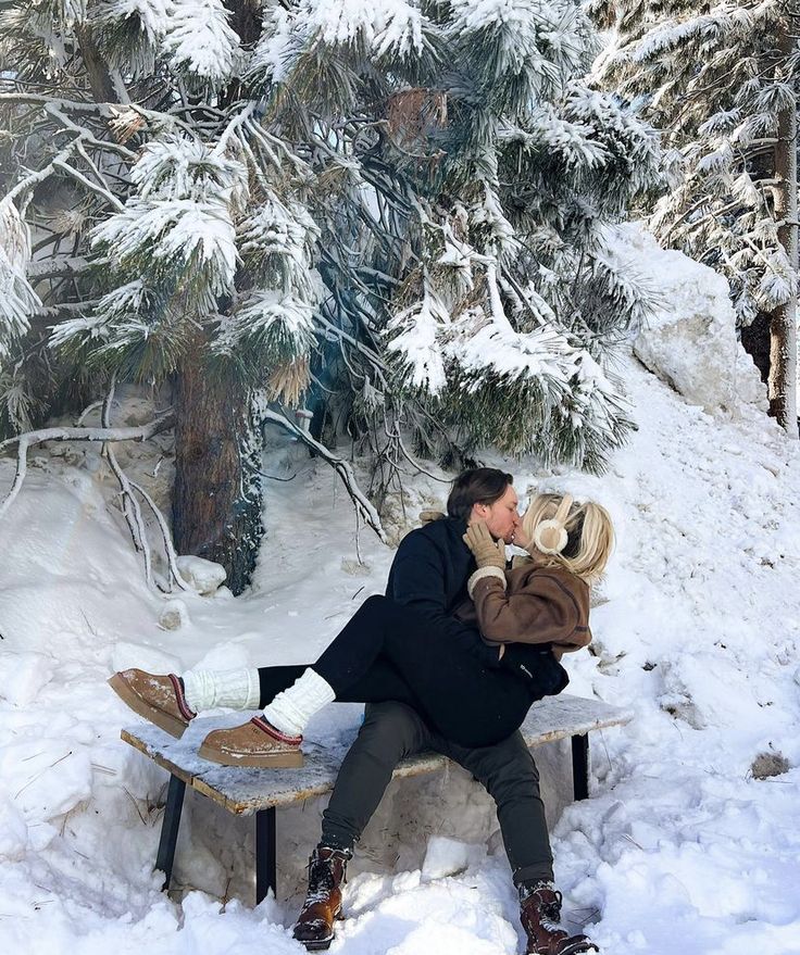 a man and woman sitting on a bench in the snow