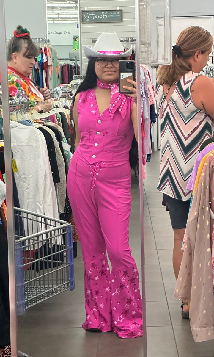 a woman is taking a selfie in the mirror while wearing pink overalls and a cowboy hat