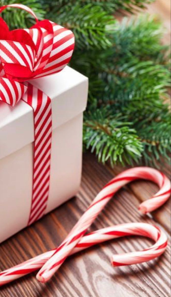 a white box with red and white striped ribbon next to candy canes