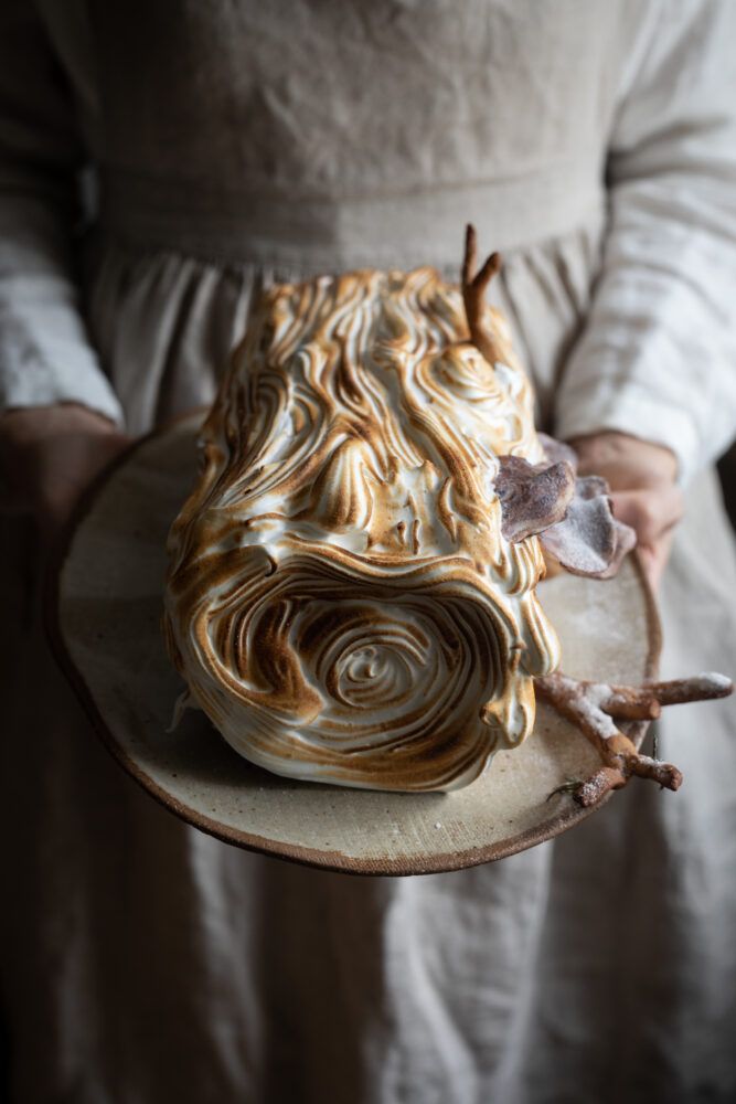 a woman holding a plate with a cake on it