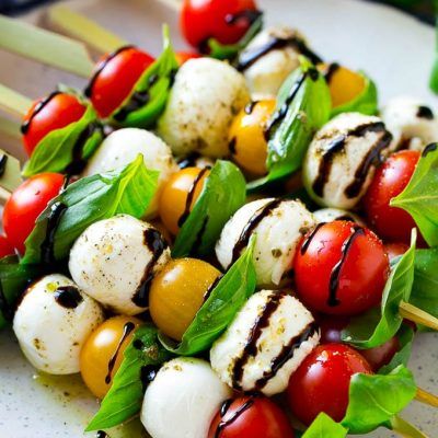 a white plate topped with lots of veggies and skewered on top of each other