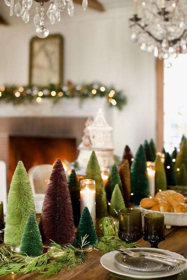 a dining room table decorated for christmas with candles and trees