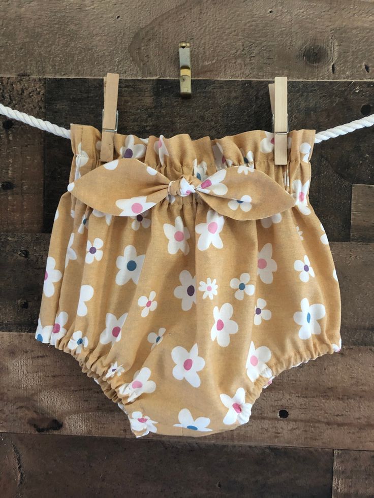 Adorable, comfortable, and soft baby boomer for your precious little love! Made of soft cotton, it is washable and durable for hours of baby fun. This bloomer has a high-waisted ruffle and elastic waistband and leg cuffs. A cute attached bow makes the front sassy and fun! (Not designed for sleepwear) Bloomers are made of 100% cotton (unless otherwise indicated) and are machine washable in warm water. Fabrics were all washed and preshrunk prior to assembly but I would recommend drying on a cool s White Cotton Bloomers With Ruffles, White Cotton Ruffled Bloomers, Cotton Bloomers With Ruffles For Spring, Spring Cotton Bloomers With Ruffles, Cotton Bloomers With Ruffles, Cute Short Diaper Cover For The Beach, Cute Short Diaper Cover For Beach, Cotton Ruffled Bloomers For Playwear, Cute Ruffled Cotton Bottoms