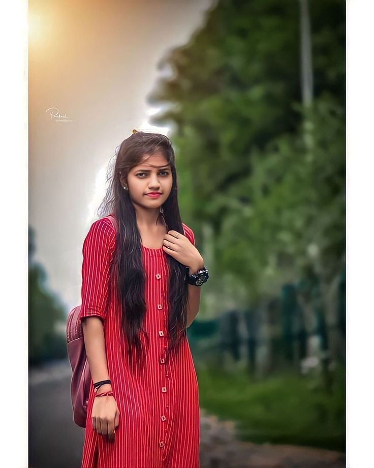 a young woman in a red dress is standing on the street with her hand on her shoulder