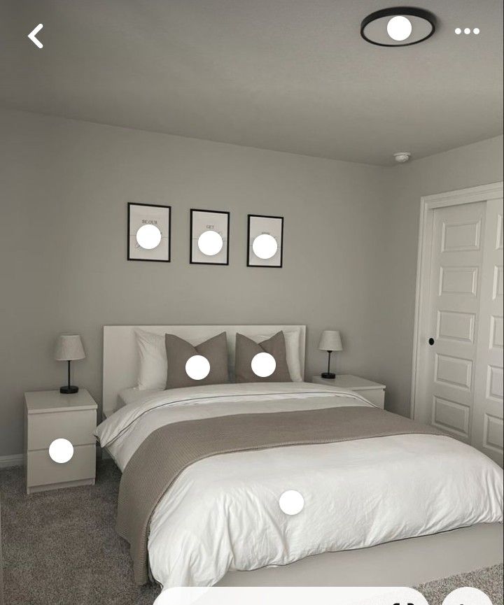 a bed with white sheets and pillows in a bedroom next to two lamps on either side of the bed