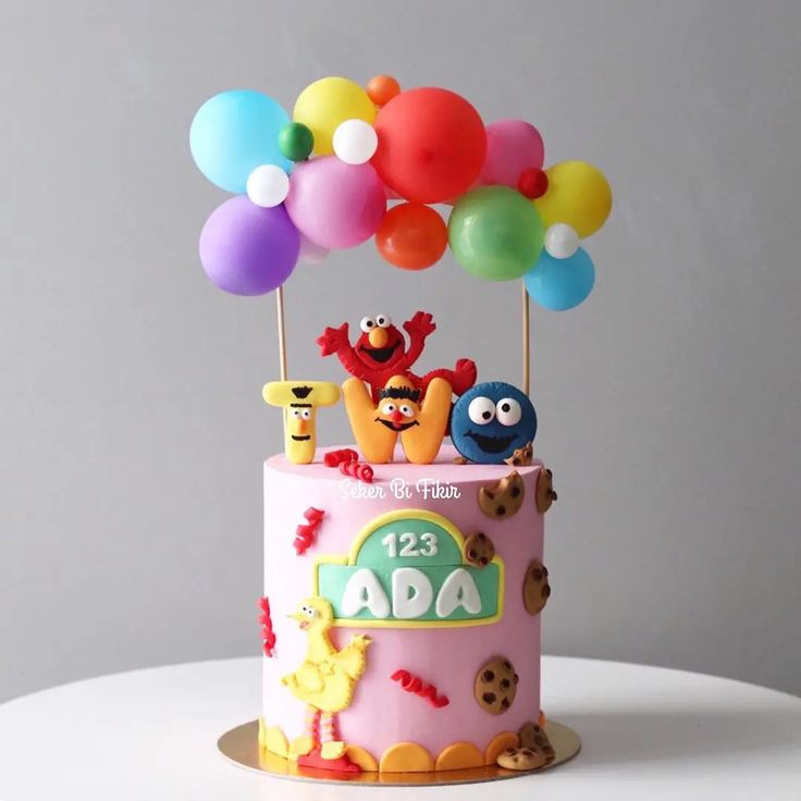 a birthday cake with sesame street characters on top and balloons in the shape of animals