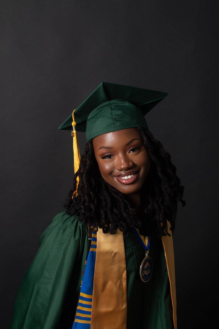 a woman in a graduation gown and cap smiling at the camera with her hands on her hips